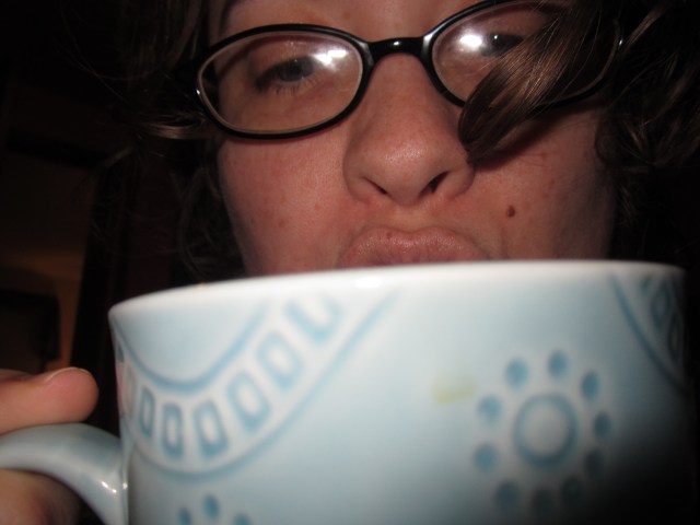 A picture of fantasy author Beth Overmyer sipping from a blue mug. Beth is the author of The Goblets Immortal Trilogy, among other works.
