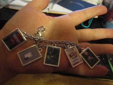 A bracelet containing the cover art of several of Beth Overmyer's books, including 'In a Pickle," "The Goblets Immortal," "Lady Catherine Says," and "Circus in a Shot Glass."